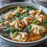 Hearty dumpling soup with tender chicken-filled dumplings in savory broth, garnished with fresh scallions.  