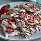 Festive strawberry yogurt bark drizzled with dark chocolate and sprinkled with pistachios, a sweet holiday delight.