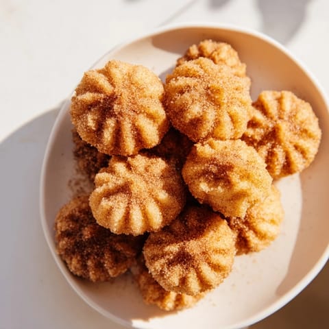 Close-up of crispy, bite-sized churro bites ready to be dipped into chocolate sauce.