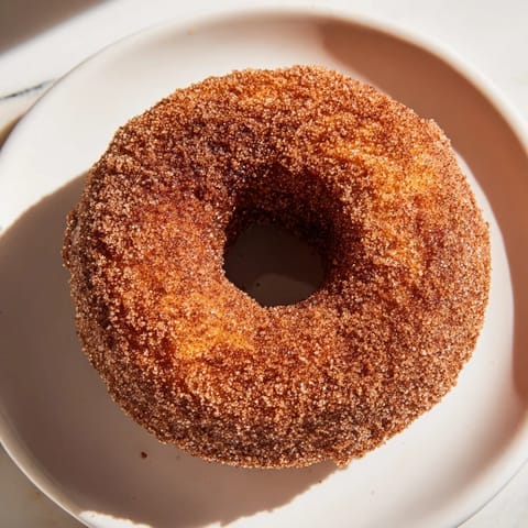 Fluffy apple cider donuts, dusted with cinnamon sugar, sit ready to be enjoyed with hot coffee.