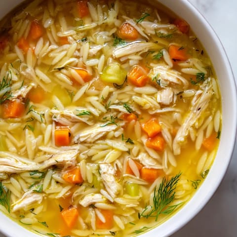 Steam rises from this comforting Chicken Lemon Orzo Soup, filled with diced carrots, celery, and zesty lemon juice.  