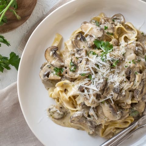 Perfect for a weeknight dinner, this vegetarian Creamy Mushroom Alfredo features golden mushrooms, garlic, and fresh parsley garnished over rich, cheesy pasta.