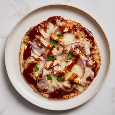 A freshly baked BBQ Chicken Flatbread on a wooden cutting board with a drizzle of extra sauce and fresh cilantro.