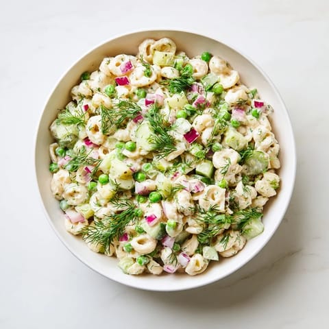 Creamy Dill Pickle Pasta Salad garnished with fresh dill and red onion, ready for a spring picnic or summer potluck.