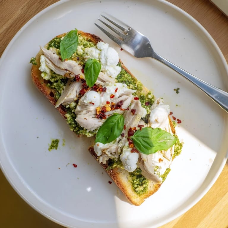 Freshly toasted sourdough slices spread with homemade pesto, piled high with juicy, seasoned chicken and melty burrata cheese for a satisfying Italian-inspired lunch.